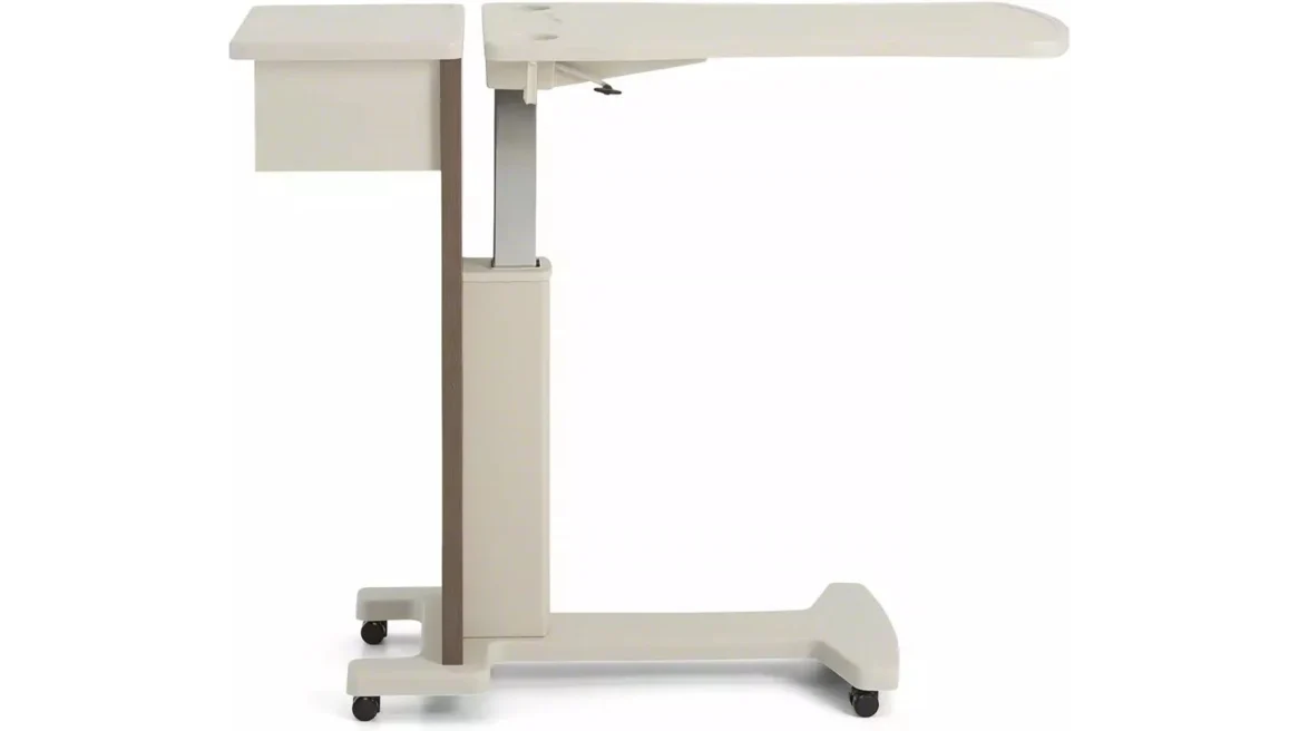Height-adjustable mobile overbed table beside a homecare bed